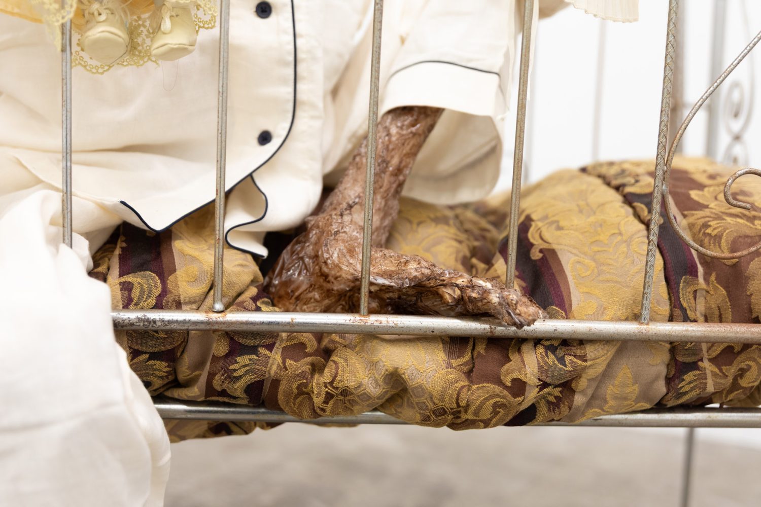 Julien Ceccaldi, Growing up Gay, 2026, Crib, comforter, plastic skeleton, melted drop cloth, wood stain, wig, acrylic paint on duralar, fake eyelashes, pyjama, and video game controller, courtesy of COOPER COLE